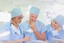 Chirurgen überprüfen Papierkram im Operationssaal — Stockfoto