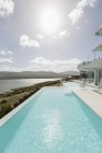 Sunny tranquilla casa vetrina piscina a sfioro esterna con vista sull'oceano — Foto stock