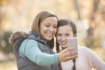 Mother and daughter taking selfie with camera phone outdoors — Stock Photo