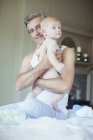 Vater hält Baby auf Bett — Stockfoto