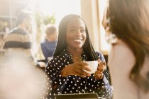 Усміхнені жінки друзі п'ють каву і розмовляють в кафе — стокове фото