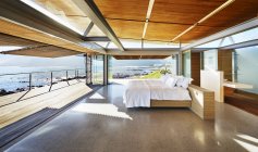 Modernes Luxus-Wohnvitrinenbett offen zur Terrasse mit sonnigem Meerblick — Stockfoto