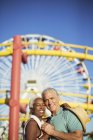Portrait de heureux couple de personnes âgées étreignant au parc d'attractions — Photo de stock