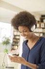 Woman listening to headphones in living room at home — Stock Photo