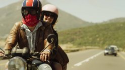 Молода пара катається на мотоциклі на сонячній дорозі — стокове фото