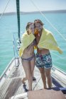 Casal compartilhando toalha em barco na água — Fotografia de Stock
