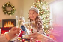 Portrait smiling girl wearing paper crown at Christmas dinner table — Stock Photo
