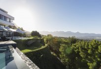 Maison de luxe moderne vitrine extérieure et piscine avec vue sur la montagne ensoleillée — Photo de stock