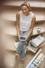 Женщина с цифровым планшетом, сидя на лестнице — стоковое фото