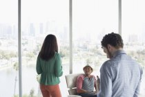 Casual business people in office overlooking city — Stock Photo