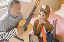 Padre e hijo tocando juntos la guitarra - foto de stock