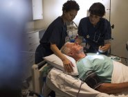Dois médicos que atendem pacientes em enfermaria hospitalar — Fotografia de Stock