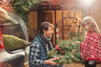 Father and daughter with Christmas wreath outside car — Stock Photo