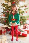 Retrato chica sonriente con traje de elfo delante del árbol de Navidad - foto de stock