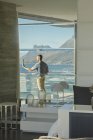 Reflexão do homem usando câmera digital tablet na varanda de luxo com vista para o mar — Fotografia de Stock