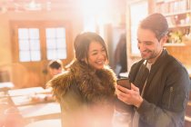 Счастливая пара с помощью мобильного телефона в кафе — стоковое фото