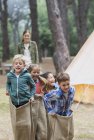 Niños que tienen una carrera de sacos en el camping - foto de stock