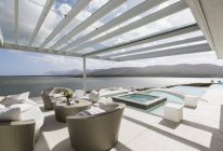 Pátio de luxo moderno ensolarado com piscina infinita e vista para o mar — Fotografia de Stock