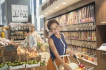 Portrait smiling young woman grocery shopping in market — Stock Photo