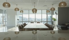Mesa de conferência e luzes pendentes na moderna sala de conferências de escritório — Fotografia de Stock
