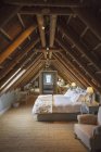Шикарная спальня на мансарде под деревянной крышей — стоковое фото
