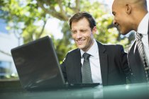 Businessmen using laptop outdoors — Stock Photo