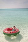 Menina retrato que flutua no anel inflável da melancia no oceano azul tropical ensolarado — Fotografia de Stock