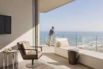 Homme bénéficiant d'une vue ensoleillée sur l'océan depuis un balcon de luxe — Photo de stock