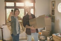 Young men roommates taking selfie moving boxes in apartment — Stock Photo