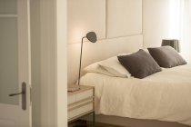 Illuminated lamp over bed — Stock Photo