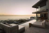 Tranquilo pôr-do-sol vista para o mar além do moderno pátio de vitrine em casa de luxo — Fotografia de Stock