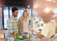 Female worker helping young couple at deli counter in grocery store market — Stock Photo