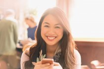Portrait smiling Chinese woman texting with cell phone in cafe — Stock Photo