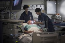 Зрелая женщина-врач и медсестра осматривают горло пациента — стоковое фото
