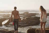 Молода пара ходить по скелях в океані — стокове фото