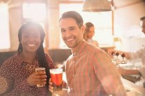 Retrato casal sorrindo beber cerveja no bar — Fotografia de Stock
