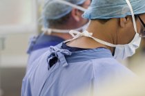 Medici che indossano berretti chirurgici, maschere e scrub in sala operatoria — Foto stock