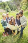 Students and teacher reading map in field — Stock Photo