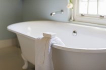 Bar soap and towel on ledge of claw foot tub — Stock Photo