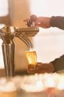 Bartender filling pint glass with beer at beer tap in bar — Stock Photo