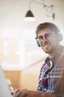 Happy young man wearing headphones and using laptop — Stock Photo