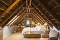Розкішна спальня на горищі під дерев'яним дахом — стокове фото