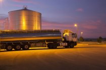Stainless steel milk tanker parked next to silage storage tower at night — Stock Photo
