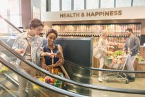 Young lesbian couple using cell phone on escalator in grocery store market — Stock Photo