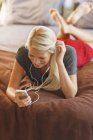 Woman listening to mp3 player on bed — Stock Photo