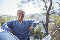 Портрет счастливого пожилого человека, опирающегося на машину — стоковое фото