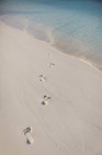 Huellas de arena en la playa tropical - foto de stock