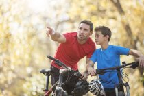 Батько вказуючи і пояснення до сина на гірських велосипедах — стокове фото