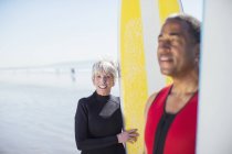 Porträt eines älteren Paares mit Surfbrettern am Strand — Stockfoto