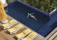 Mulher flutuando na piscina de luxo — Fotografia de Stock